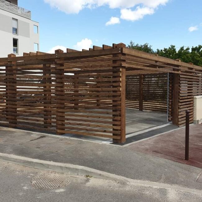 Abri cache contener développé avec un maitre d'eouvre. Les façades sont à claires voies et l'ouverture par un portail coulissant acier bois